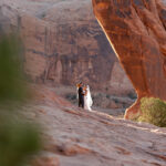 Bride and groom walking on the red sand in Moab Utah