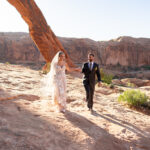 Moab elopement of the arches at sunrise bride and groom holding hands