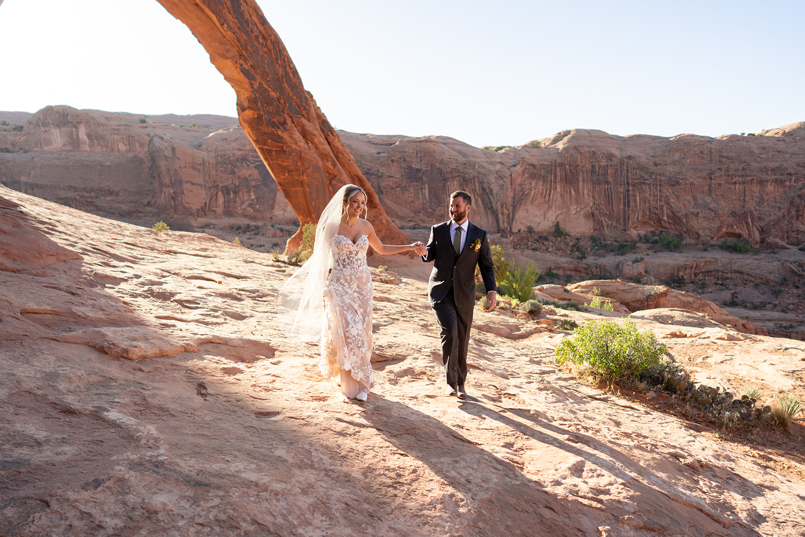 Moab elopement of the arches at sunrise bride and groom holding hands