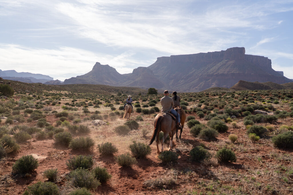Horseback riding in canyon at sunrise — Couple riding horses through a private canyon trail during their Moab, Utah elopement.