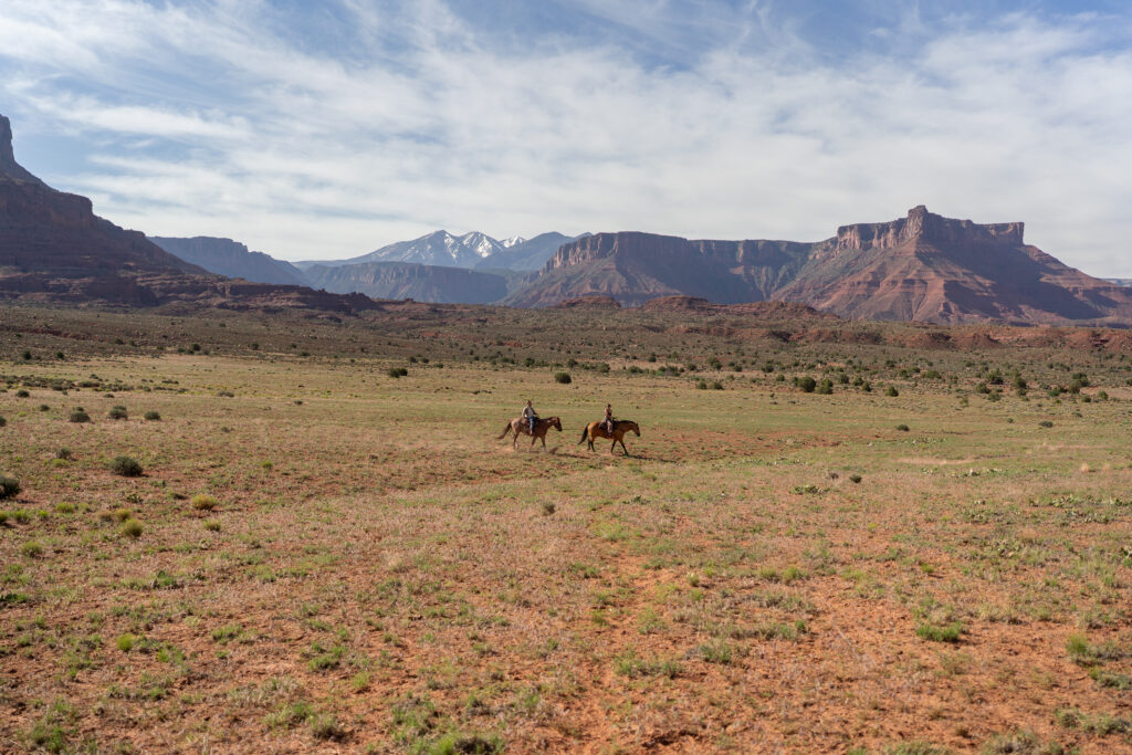 Horseback riding in canyon at sunrise — Couple riding horses through a private canyon trail during their Moab, Utah elopement.