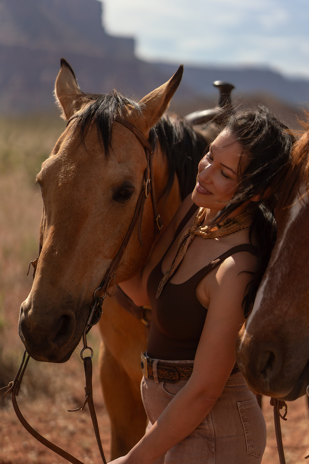 Close-up portrait of the bride with her eyes closed and She is wearing a brown top and bandana. Moab elopement with Red Cliffe Horses.