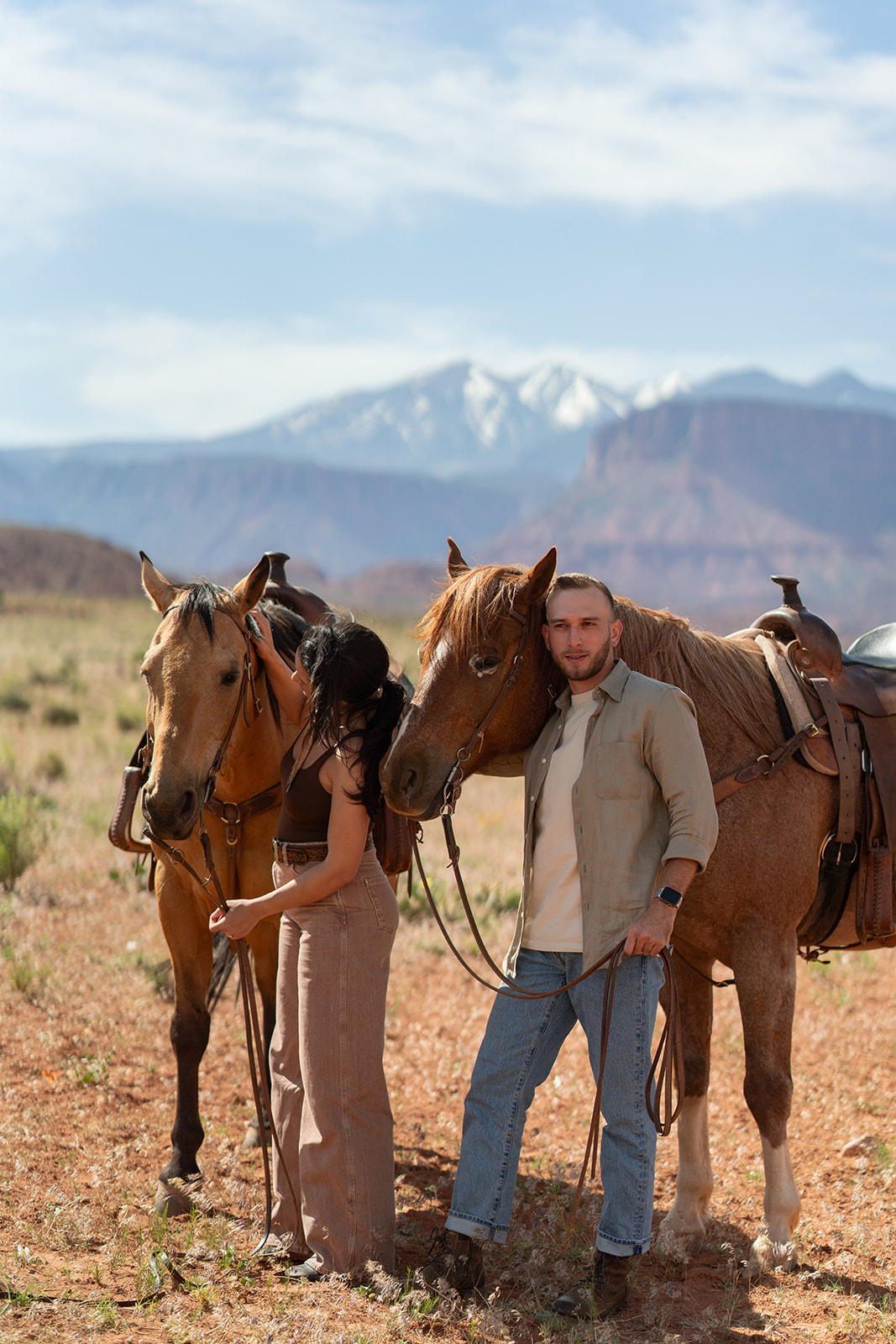 Couple standing close to their two horses in the Utah desert