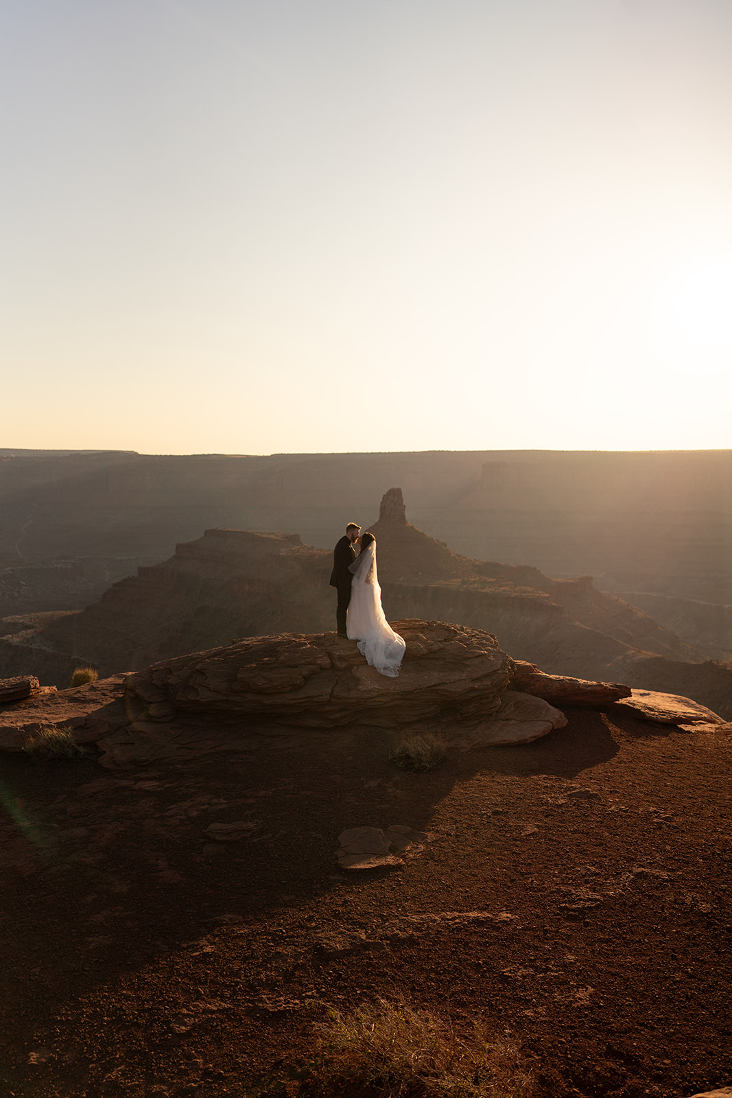 A couple on a cliff overlooking a vast canyon in Utah, a popular destination for elopements