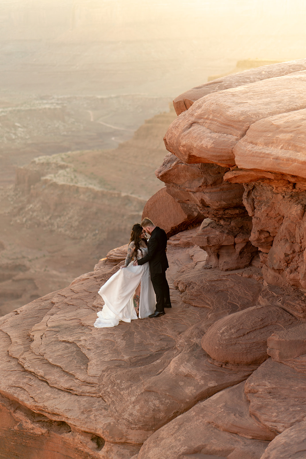 A couple embracing between large red rock formations in Utah, perfect for a secluded elopement.