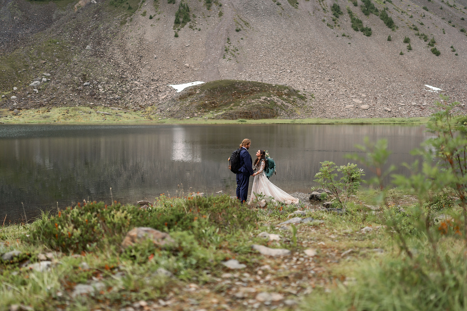 A newly wed couple holding hands by a misty mountain lake in the US