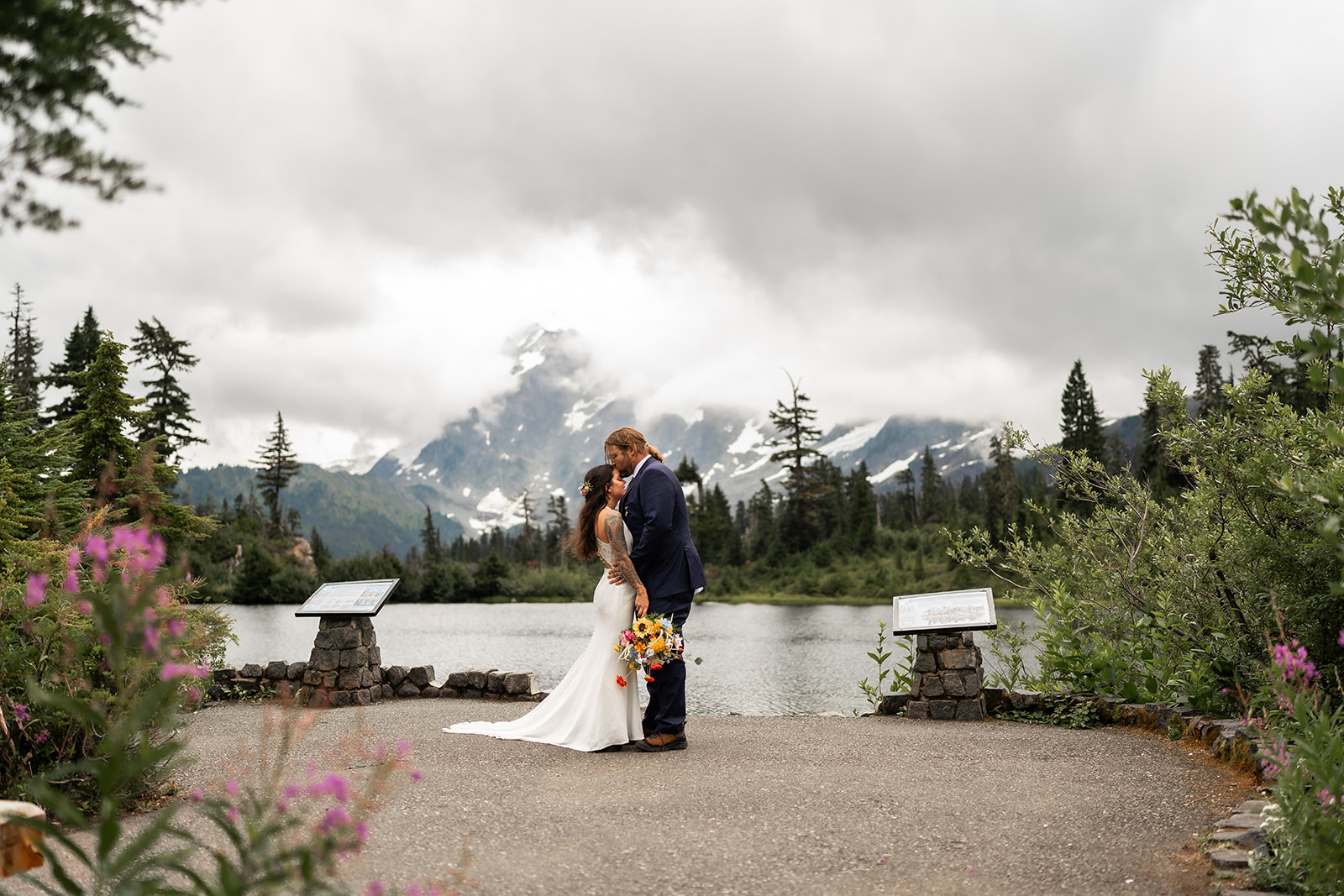 A couple kisses in front of a mountain lake, a perfect scene in the US.