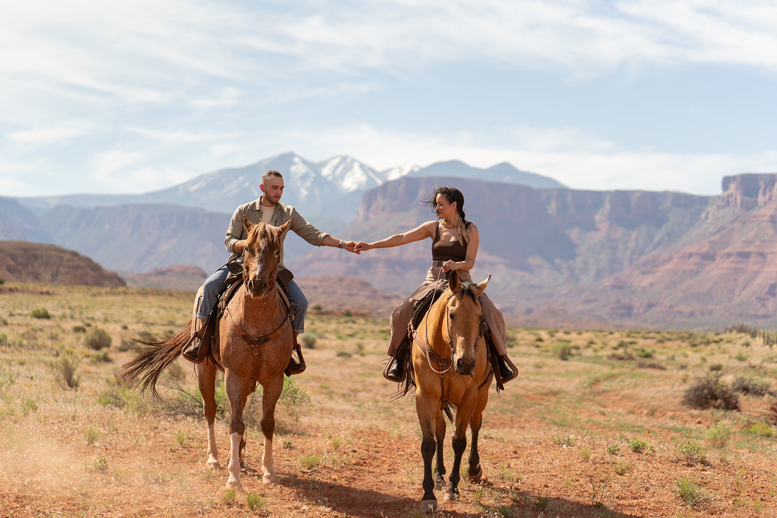 Couple riding horses together in the stunning Utah desert, ideal for a memorable all-inclusive elopement