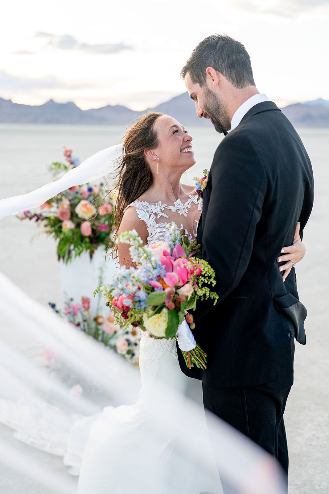 A couple embracing at their all-inclusive elopement with a colorful floral arrangement