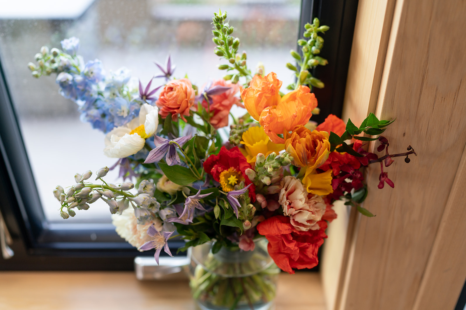 Vibrant spring-colored wedding centerpiece or accent arrangement by Tangled Sage Event Artistry, showcasing ranunculus, poppies, and delphinium flowers a moab elopement florist