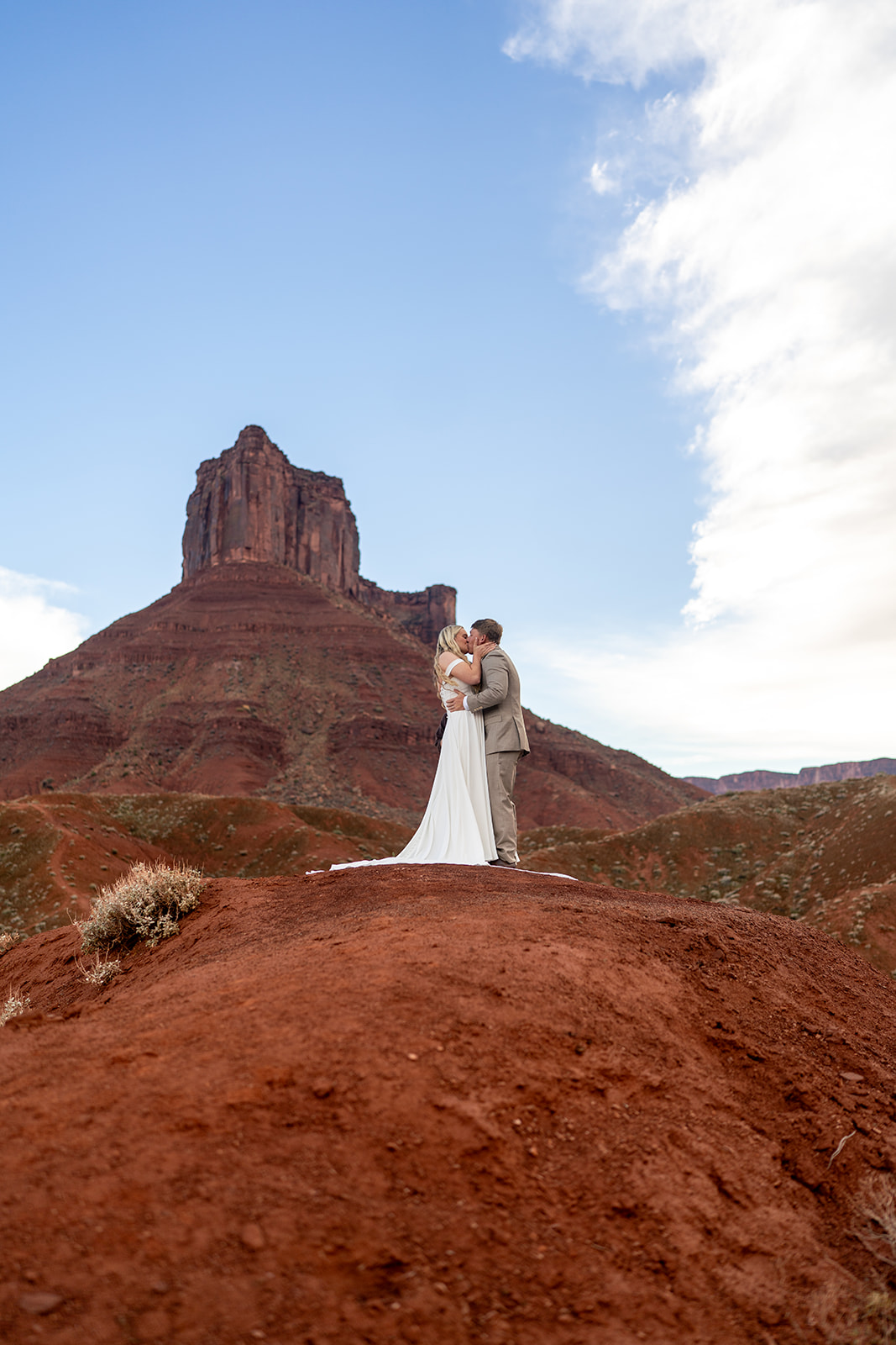 Bride and groom kissing on a red rock hill in Moab Utah