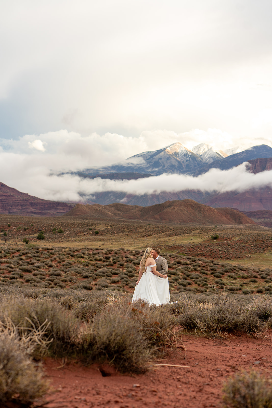 Adventure elopement couple kissing in a vast Moab, Utah desert landscape understanding The Cost to Elope in 2025 as told my utah elopement photographer hannah rita